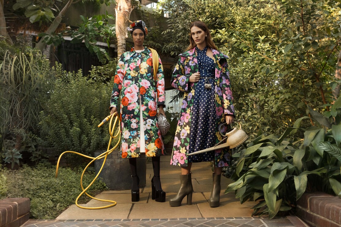 Models wear colourful coats in a green garden