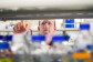 Patrick Aloy lidera el laboratorio de Bioinformática Estructural y Biología de Redes del IRB Barcelona. Patrick está situado detrás de una estanterí de laboratorio con botes que tienen tappones azules. La estantería y los botes aparecen difuminados y Patrick detrás señalando uno de ellos. Patrick tiene el pelo corto y lleva gafas y una camisa azul.