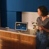 Woman in a kitchen holding a coffee and talking to Alexa+ on Echo device 