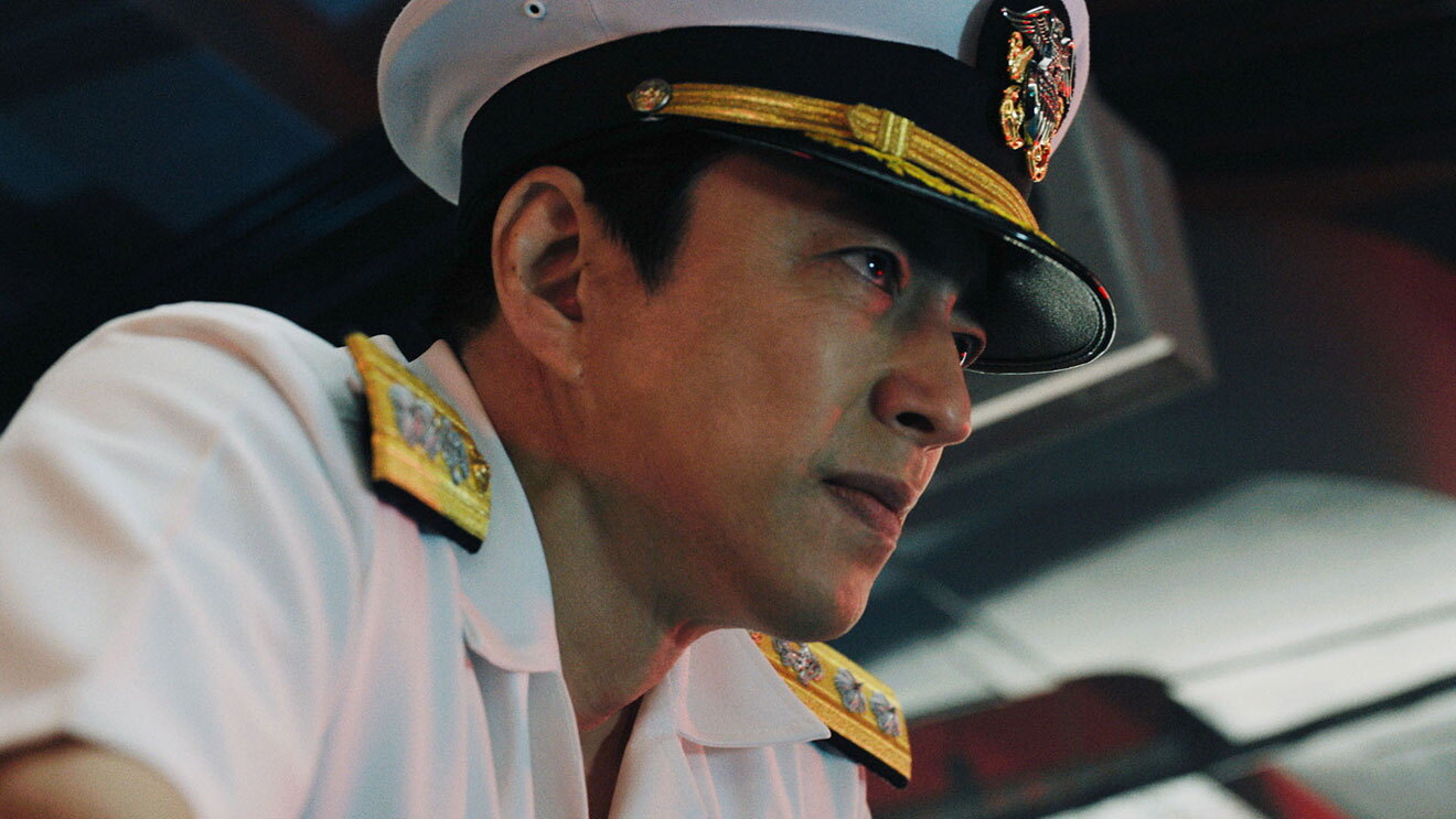 薄暗い室内、白い海軍の制服と制帽を着用した男性の横顔。斜め下から見上げた角度で、男性は右側を向いている。