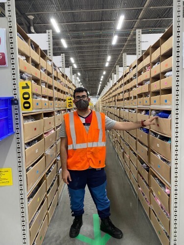 Shams Hussamy, an Amazon Associate, stands for a photo in the fulfillment center where he works in Ontario.