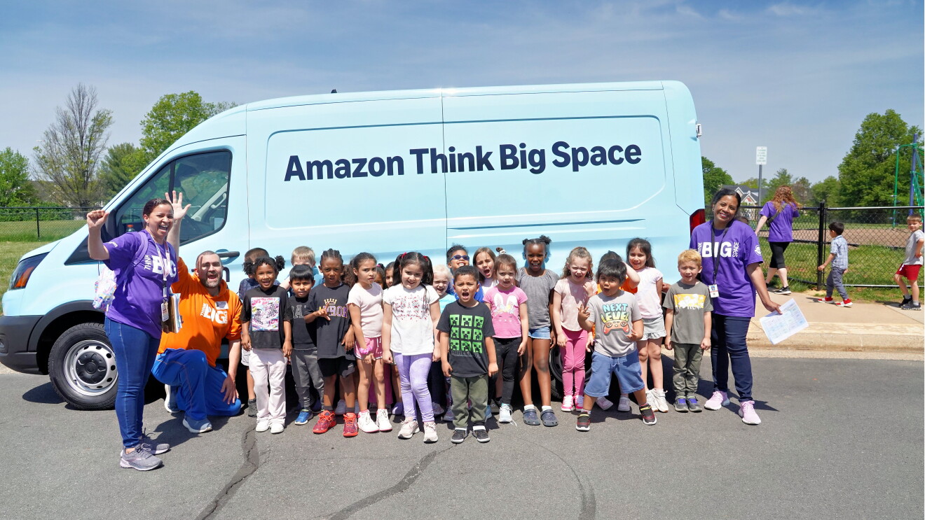Group of children with adults posed in front of Amazon Think Big Space van
