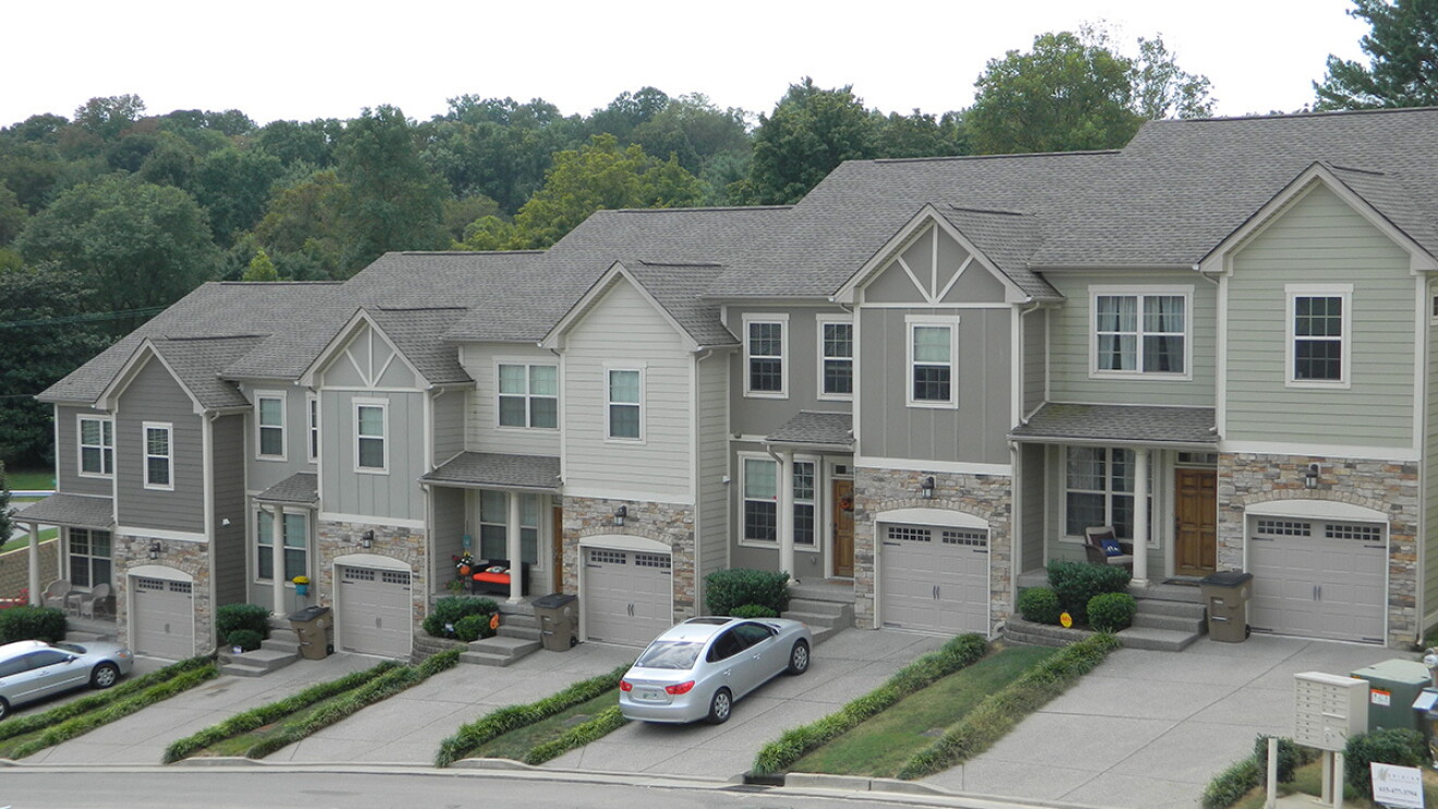 Five townhouses lined up in a suburban setting. 