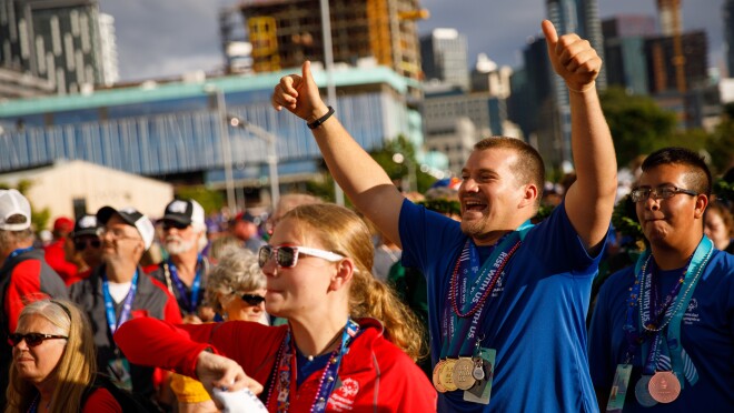 特殊奥林匹克运动会的运动员和闭幕式与会者庆祝。许多人看向舞台,男运动员放弃拇指而微笑。