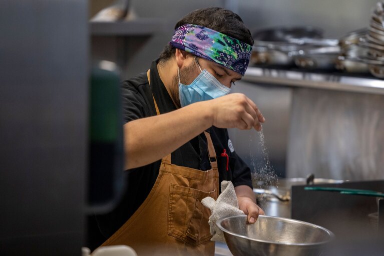 A cook at Eastvale Cafe prepares food in a kitchen.