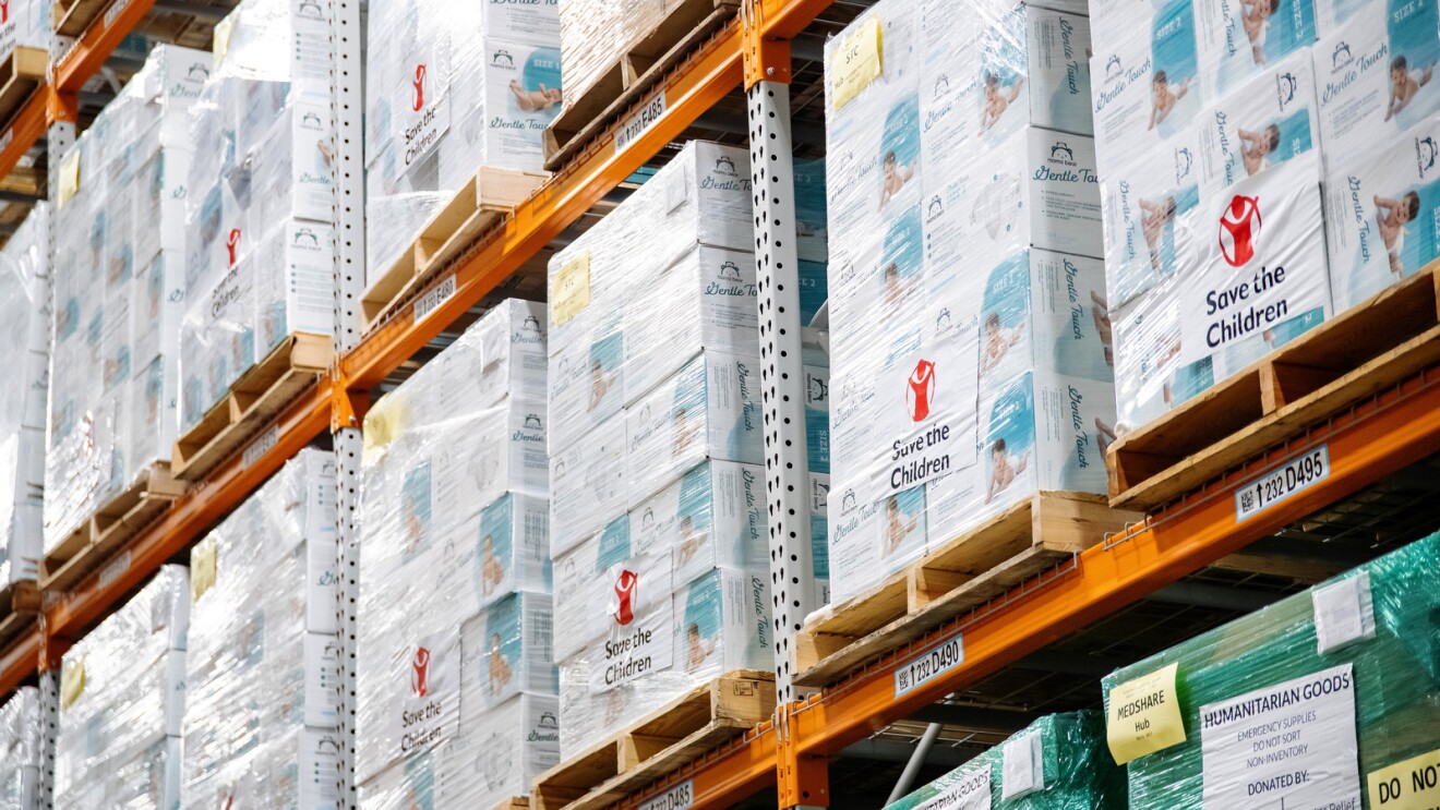 An image of items stacked on shelves in an amazon fulfillment center. They are labeled according to the charities they will be donated to.