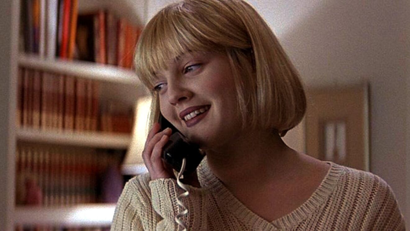 Drew Barrymore with blonde bob haircut smiling while talking on corded phone in Scream franchise