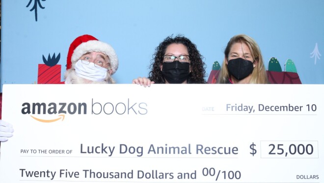 圣诞老人和两个女人举起一个超大号的检查做幸运儿救援从亚马逊图书为25000美元。