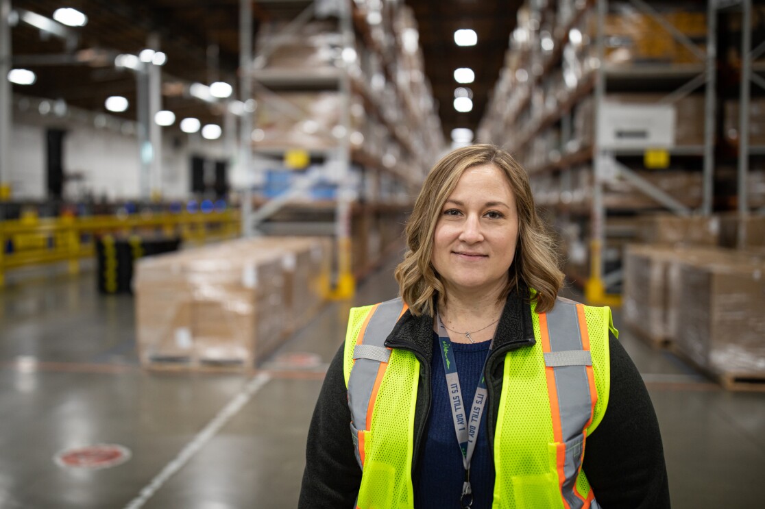 A woman in a high-visibility vest looks directly at the camera