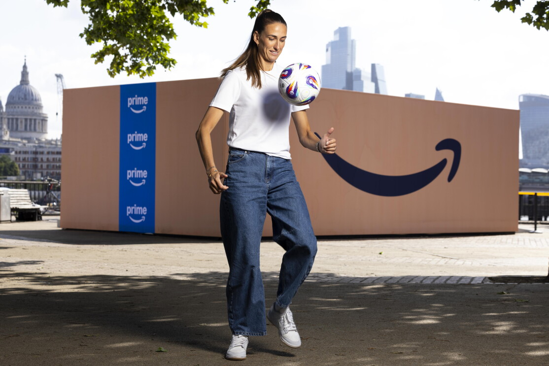 Jill Scott playing with a football at the front of a giant Amazon Prime box. 