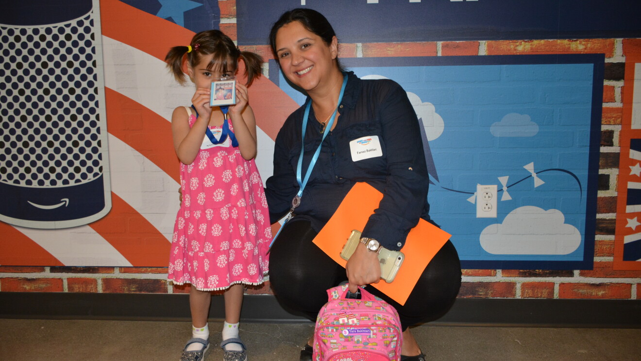 A female Amazon employee crouches down next to her daughter for "Bring your kids to work day."