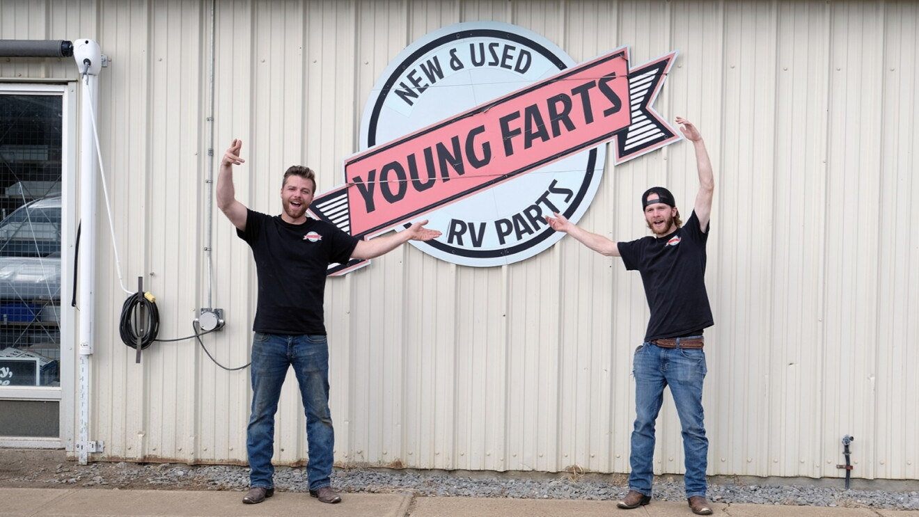 Two employees standing in front of 'Young Farts Trailer Parts'