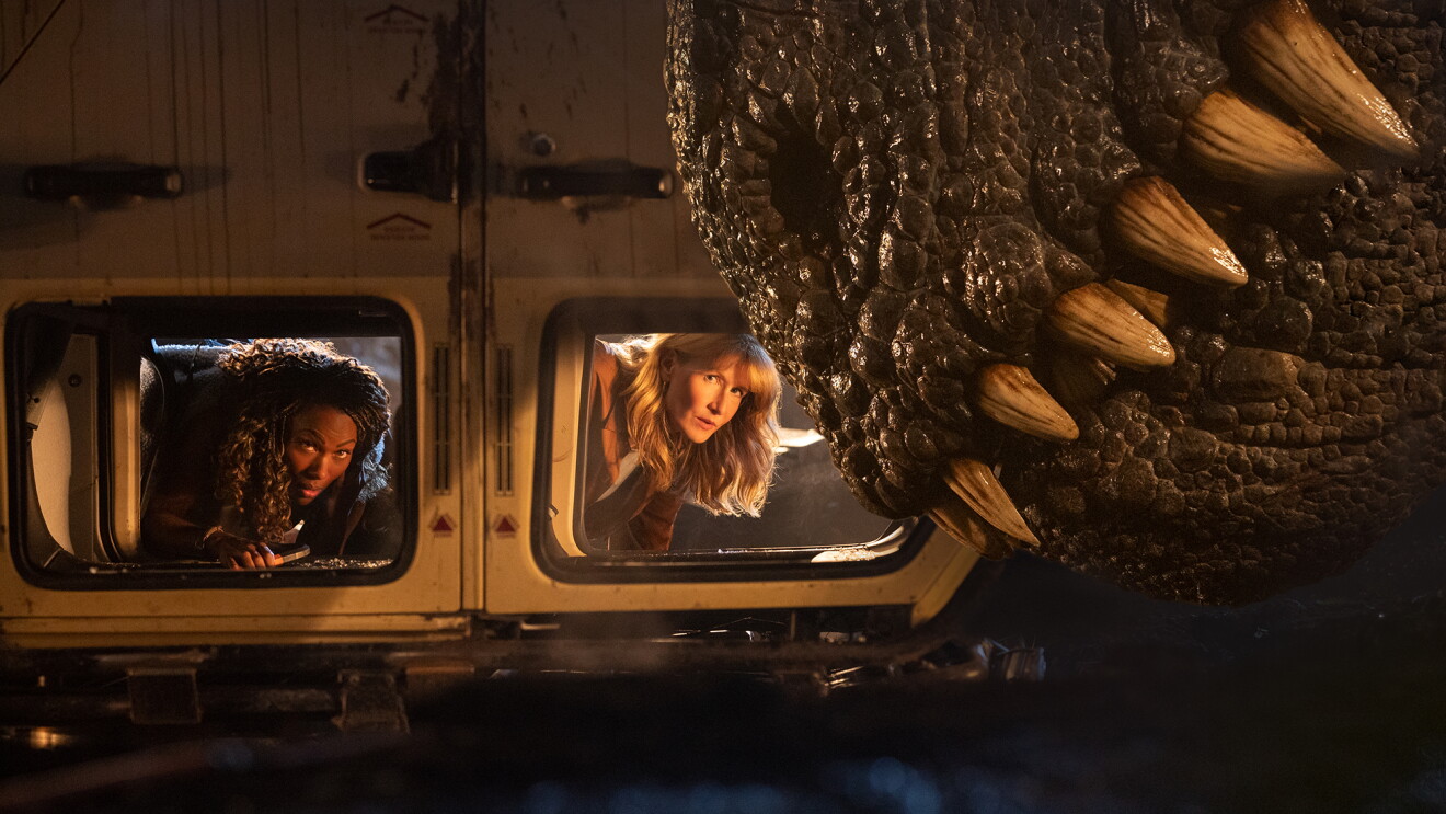 Two women peering anxiously from train windows as giant dinosaur claws loom nearby.