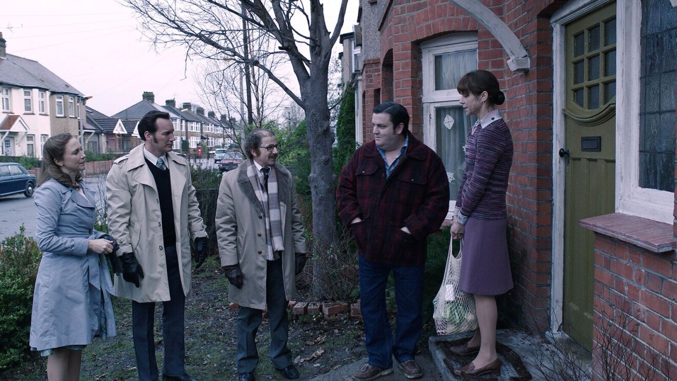 The Conjuring movie: Group gathered outside brick house on suburban street