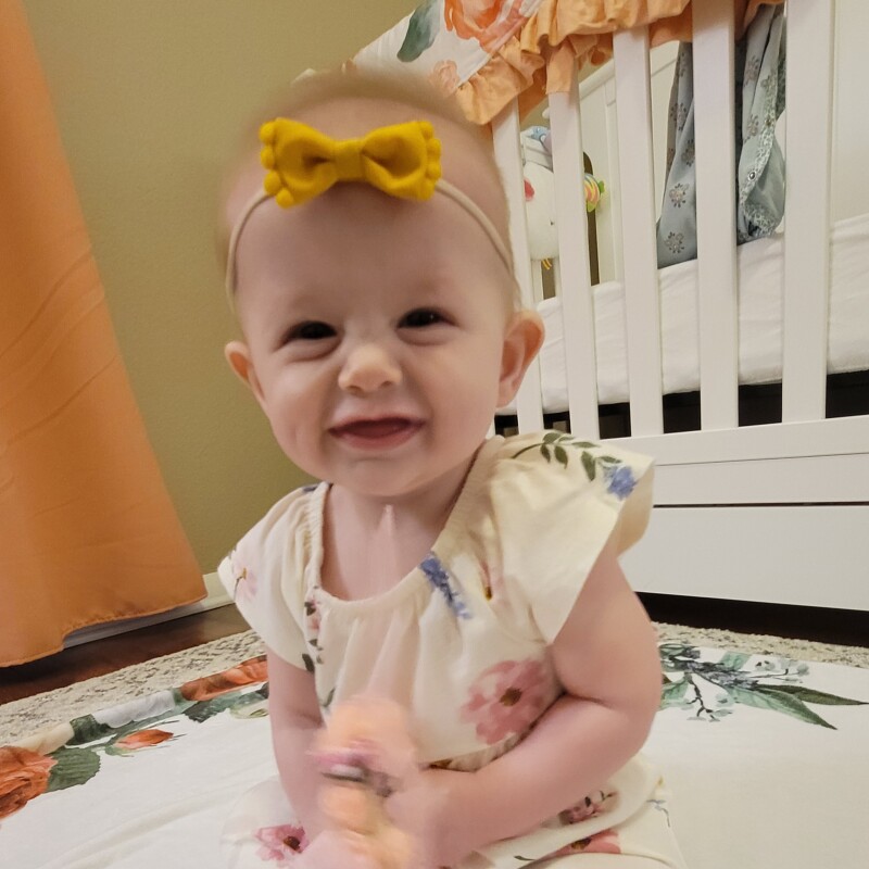 A woman and her husband pose and smile with their infant daughter