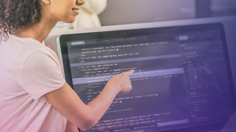 l'immagine mostra una donna che indica uno schermo di pc che mostra linguaggio di programmazione