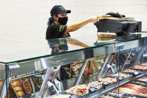 An image of a woman working at a counter in an Amazon Fresh store.