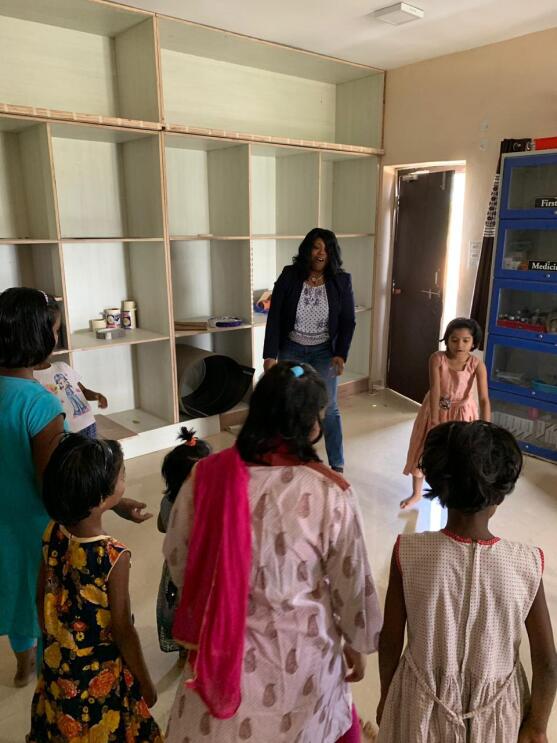 An image of Nancy Dalton visiting children in an orphanage. They are standing in a circle in a classroom speaking to each other. 