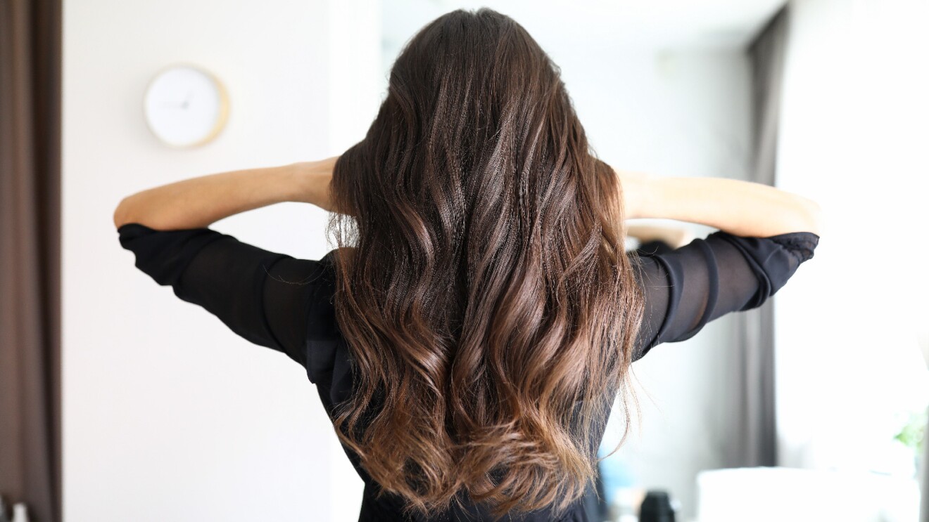 Prime Day 2023 live blog best deals: posterior image of a woman pushes back her long, brown hair.