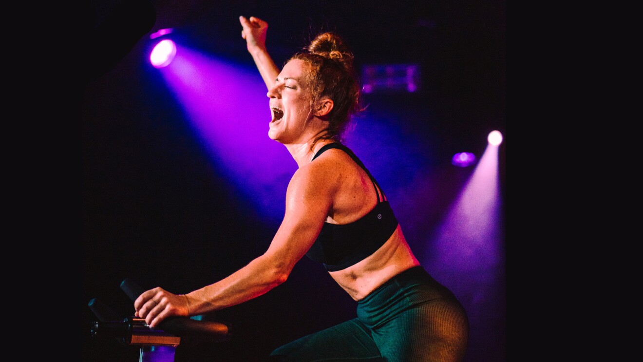 A photo of HUSTLE Fitness founder, Sunny Miller exercising on a stationary bike.