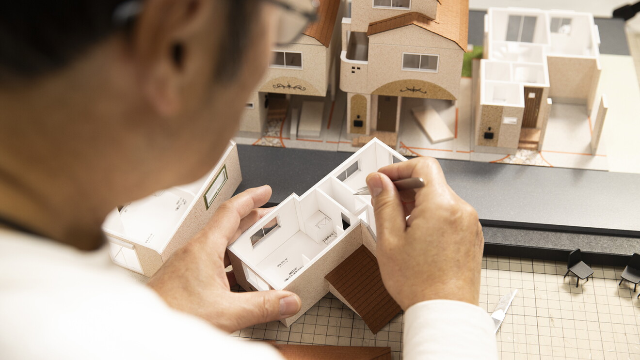 ピンセットで住宅の模型を組み立てている男性