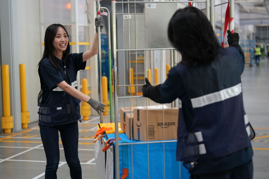 広い倉庫のような空間で女性2人が荷物が載せられたカートを移動させている