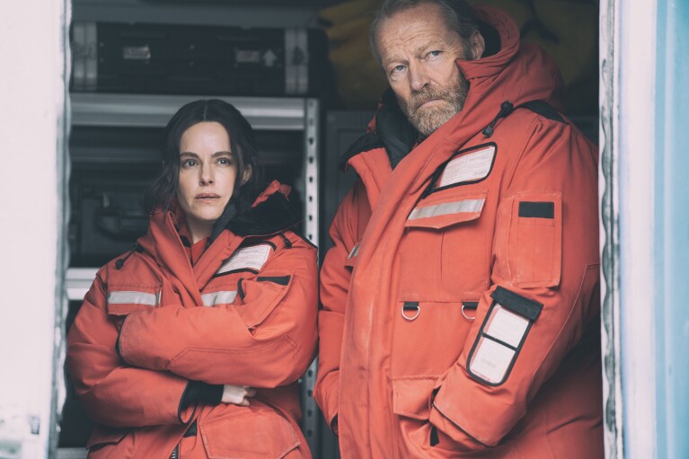 Emily Hampshire and Iain Glen wearing wearing orange jackets in The Rig Season 2