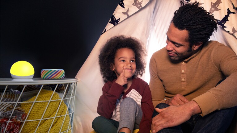 An image of a father and son with two Echo devices on a nightstand next to them.