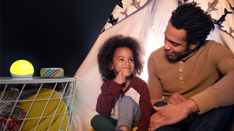 An image of a father and son with two Echo devices on a nightstand next to them. 