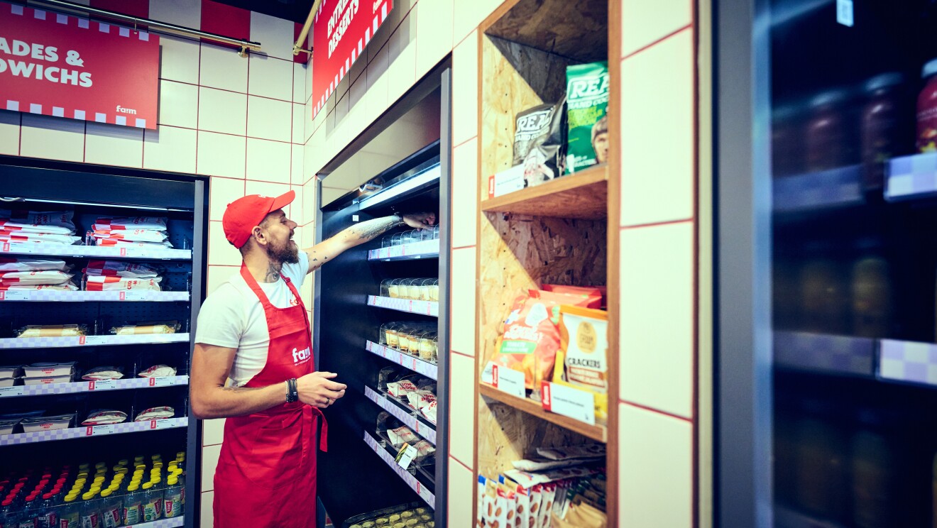 Membre du personnel rangeant des produits dans le rayon réfrigéré du magasin