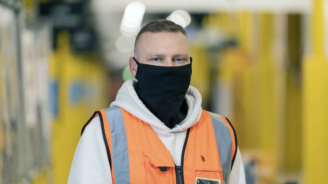 Marcin Jeznach wearing a mask and high-vis jacket in an Amazon Fulfilment Centre.
