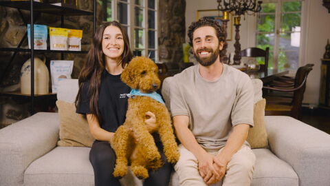 A man and woman sitting on a couch with a dog