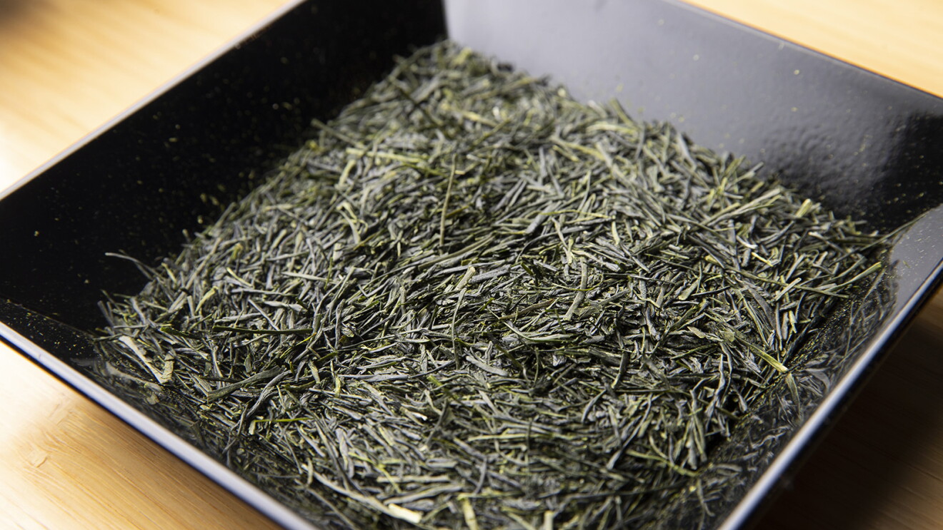 細く深い緑色をしたお茶の葉が黒いお皿に盛られている
