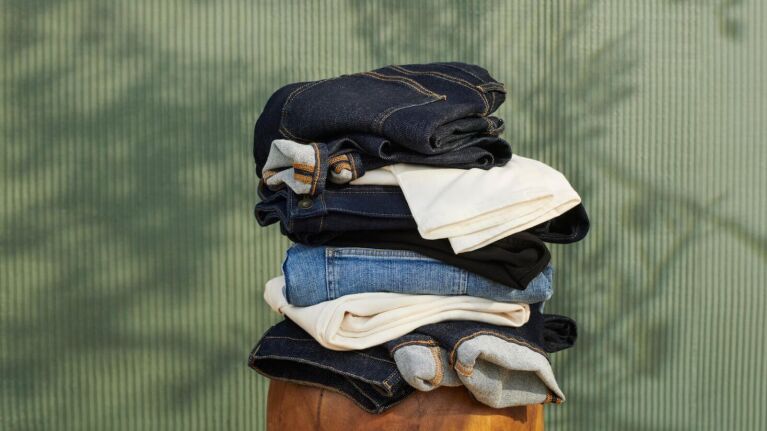 Stack of folded denim, beige, and black clothing items