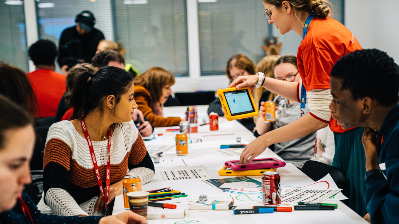 Row of children from Barnardo's doing arts and crafts at robotics workshop. They are also being handed tablet computers.