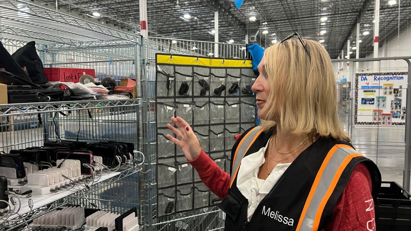 An image of a woman, an Amazon Delivery Service Partner, in a work vest standing in front of a delivery van.