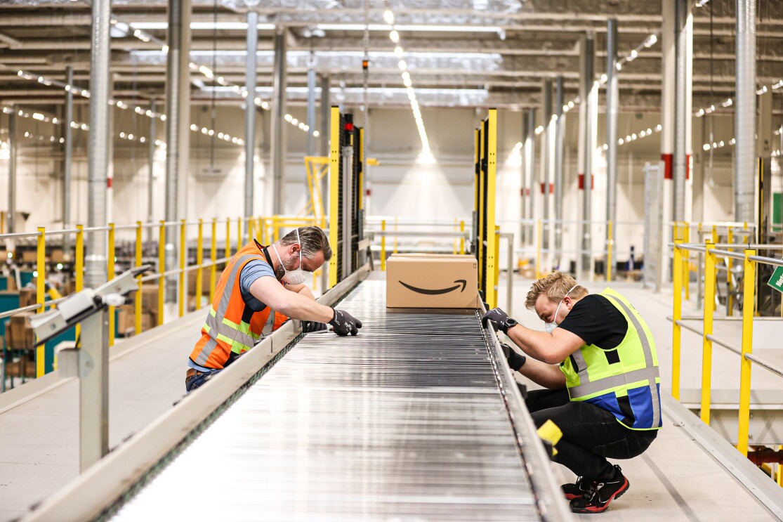 Two engineers assembling a track with Amazon package in background.