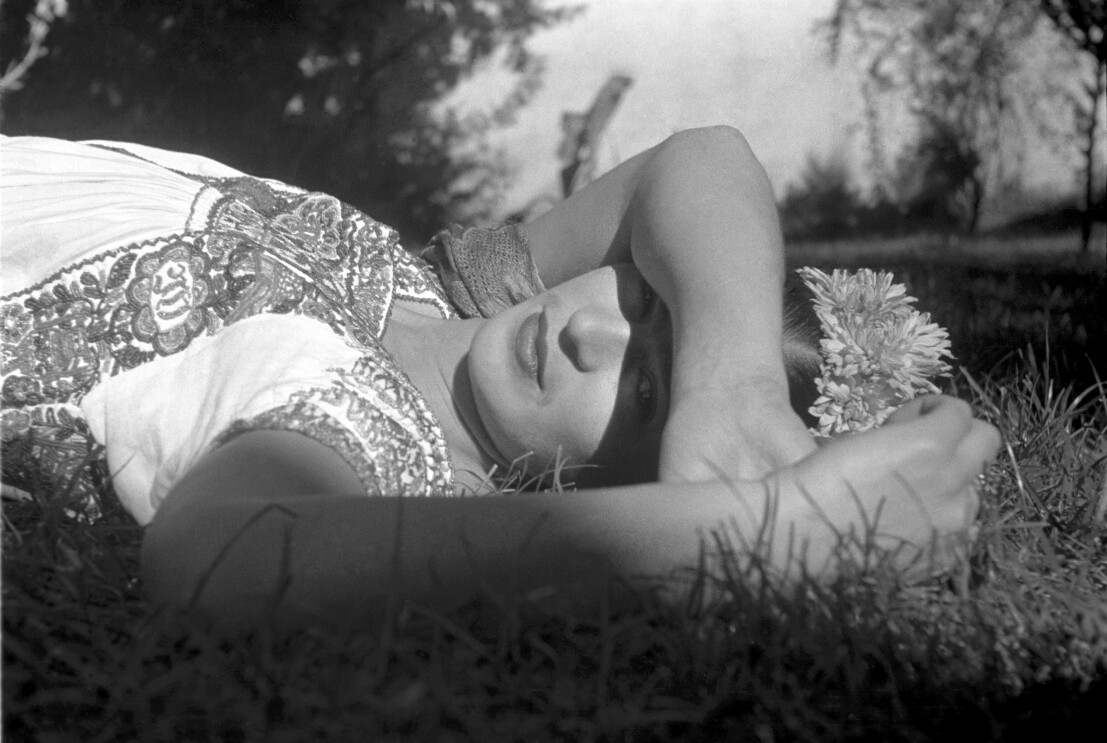 Frida Kahlo lying on the grass with her arm over her face