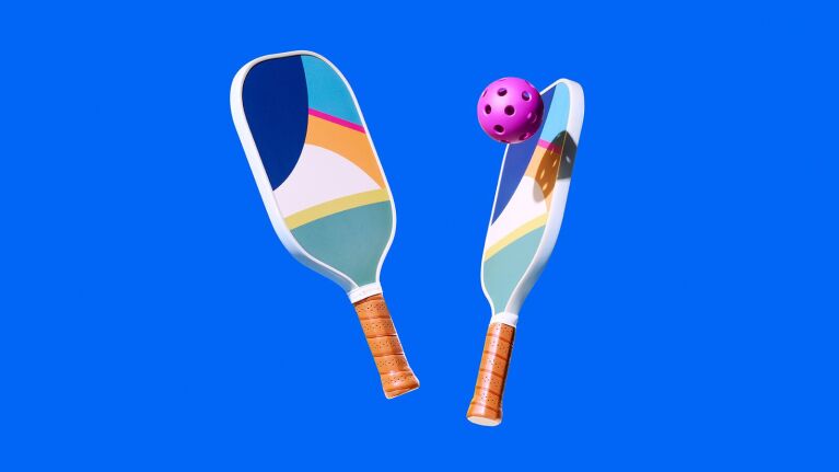 Colorful pickleball paddles and ball against bright blue background