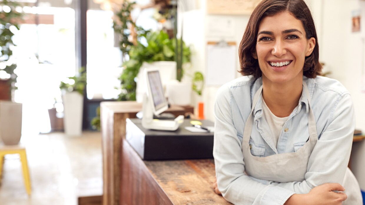 Portrait Of Smiling Female Sales Assistant Standing Behind Sales Desk Of Florists Store