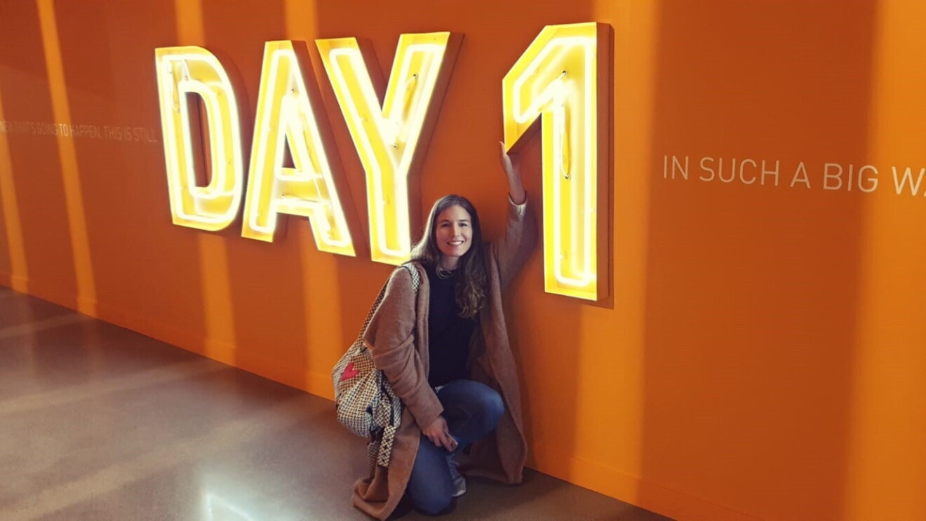 Eine Gewinnerin der Unternehmerinnen der Zukunft-Reise nach Seattle, sitzt vor einer orangenen Wand mit einer großen Leutschrift: Day 1