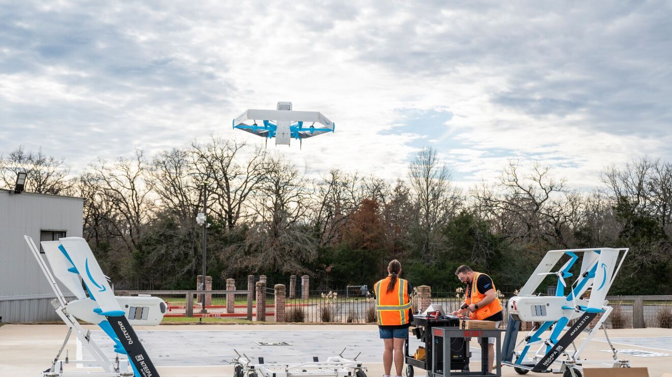 An employee loads a package into a delivery drone before it takes flight