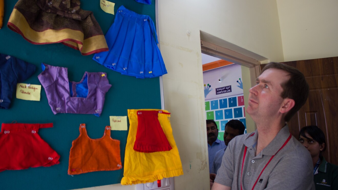 John Felton looks at some clothes stitched by women at the Community Centres.