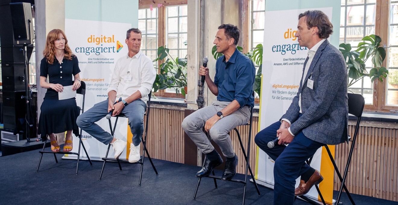 Moderatorin Teresa Sickert, Lars Schmitz (Amazon Web Services), Rocco Bräuniger (Amazon) und Holger Krimmer (Stifterverband) (v.l.)  sitzen auf der Bühne der digital.engagiert-Abschlussveranstaltung und tauschen sich aus.
