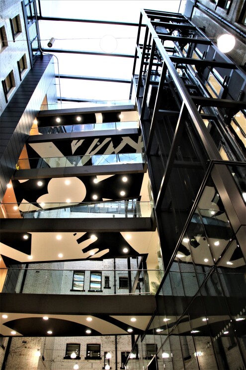 A modern multi-story atrium with glass elevators and artistic lighting