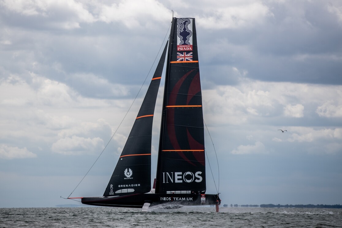 An image of the AC75 challenger boat being tested out on the water. The boat has the INEOS Team UK branding on it.