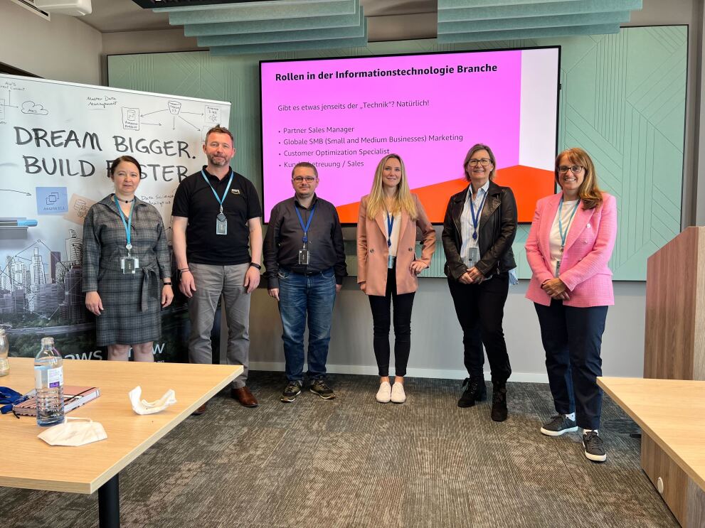 Gruppenbild des Teams von AWS beim Wiener Töchtertag 2022 vor einem Plakat mit der Aufschrift "Dream bigger. Build faster" und einer Leinwand mit der Aufschrift "Rollen in der Informationstechnologie Branche". Zu sehen sind Agnes Balaz, Alex Matai, Andreas Juffinger, Petra Wolf, Hildegard Kerschbaumer und Nina Michor.