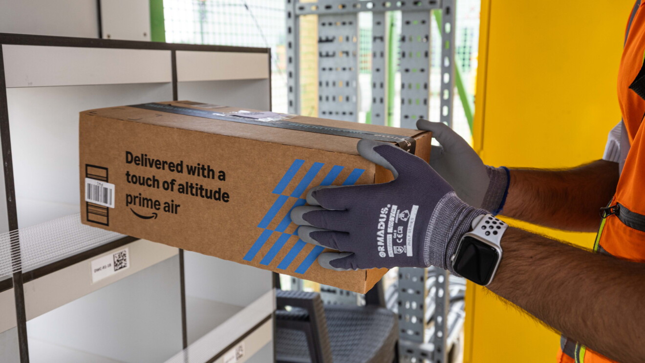 A Prime Air box being put on a shelf by an Amazon worker