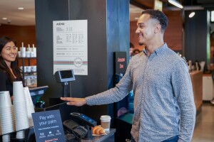 A photo of a customer purchasing a coffee and croissant with Amazon One.