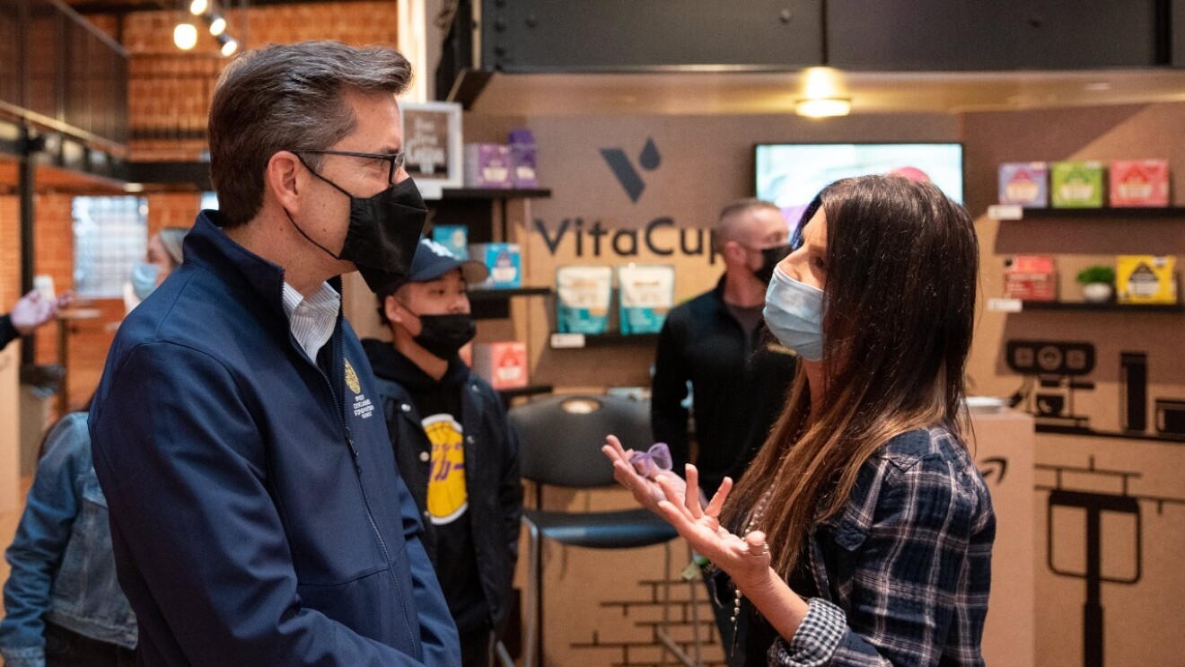 A woman wears a face mask while talking to a man wearing a face mask at the Shop Local event.
